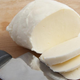 mozzarella cheese being sliced on cutting board